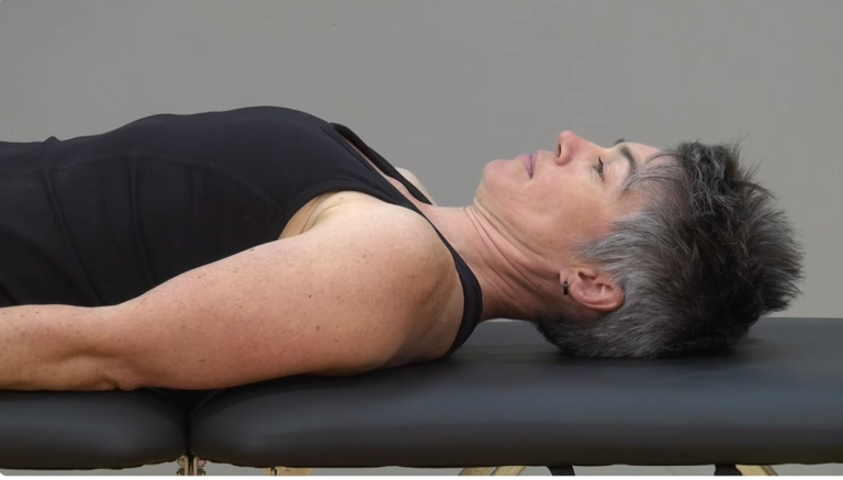 Image of a woman performing a lying neck stretch