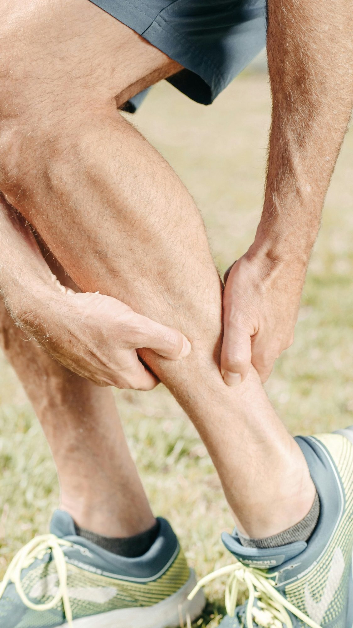 Image of a man's leg and his hands grasping his calf in pain