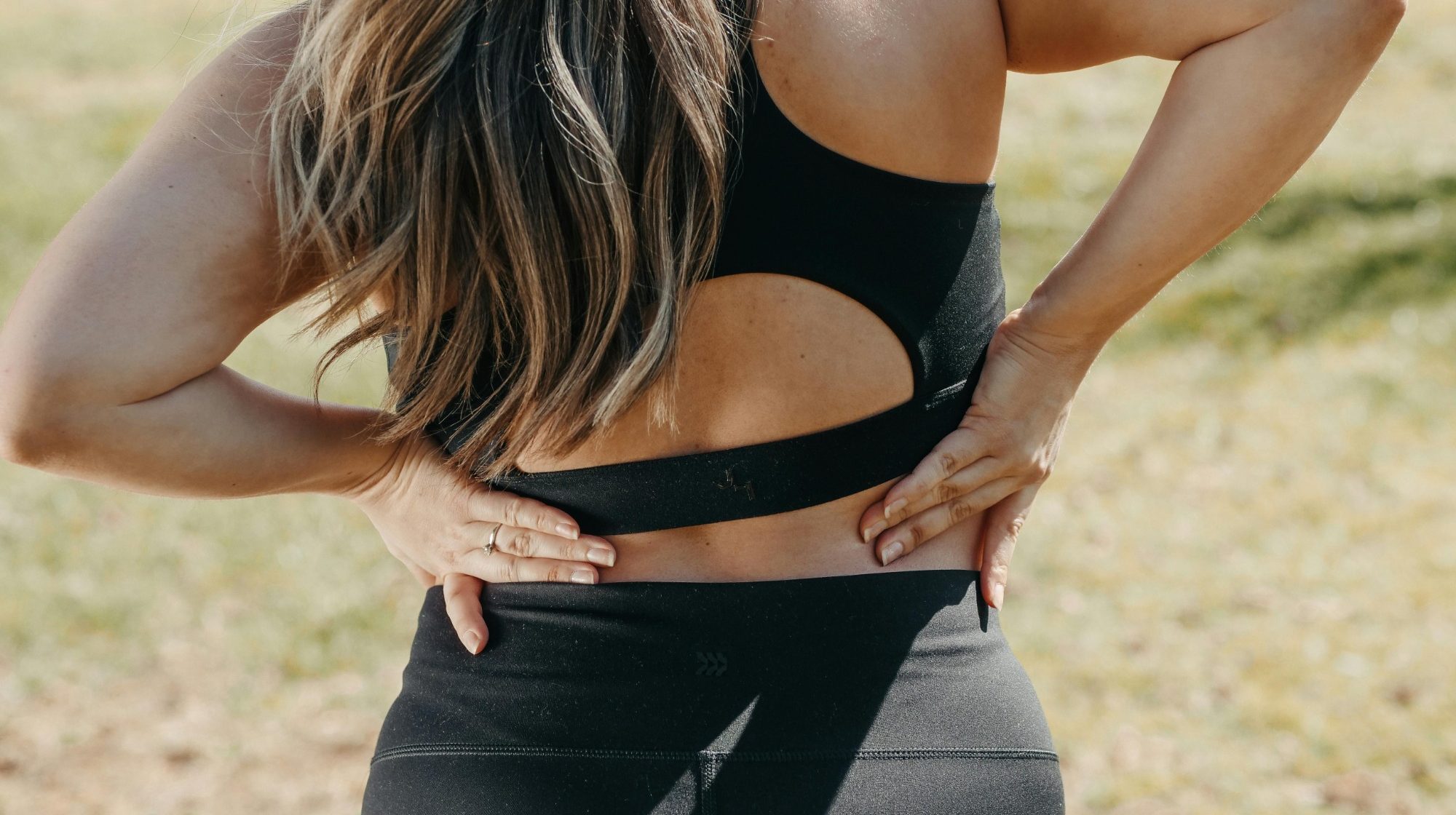 Image of a woman's back with her hands reaching down indicating that she's in pain