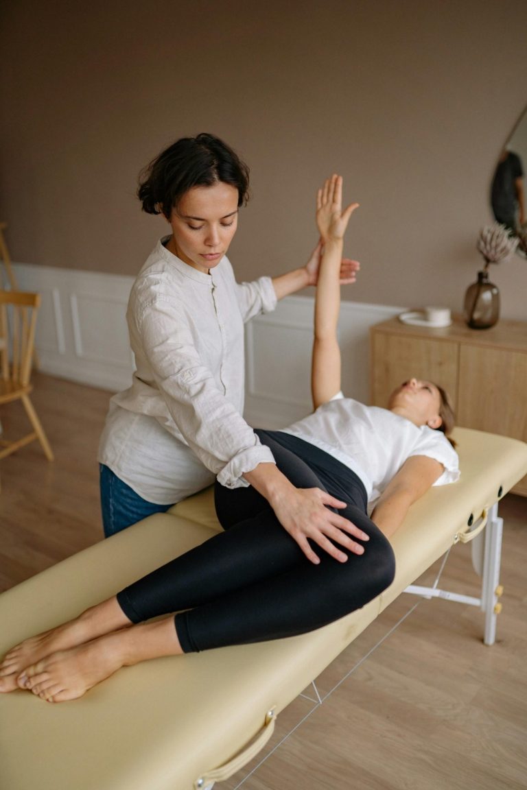 Image of a female physiotherapist stretching a woman on a massage table