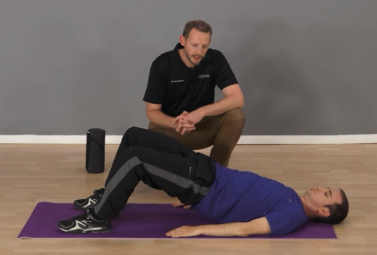 Image of a man performing the glute bridge exercise with a personal trainer